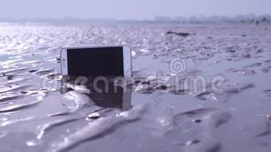智能手机卡在海滩的潮湿沙滩上